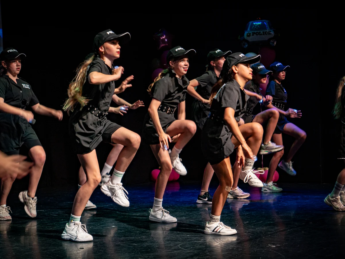 Oudere Rebounce-dansers in zwarte kostuums met petjes tijdens de eindvoorstelling