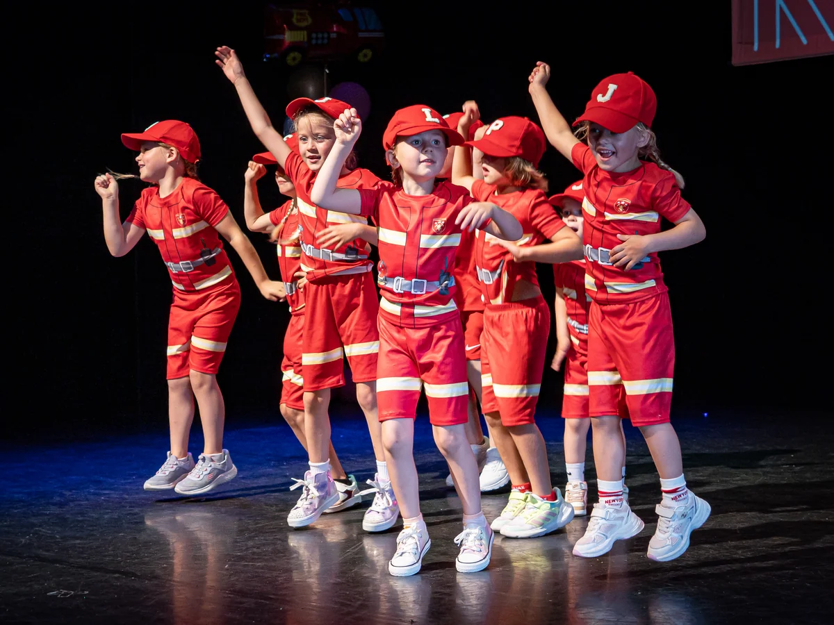 Jonge Rebounce-dansers springen in rode kostuums tijdens de eindvoorstelling