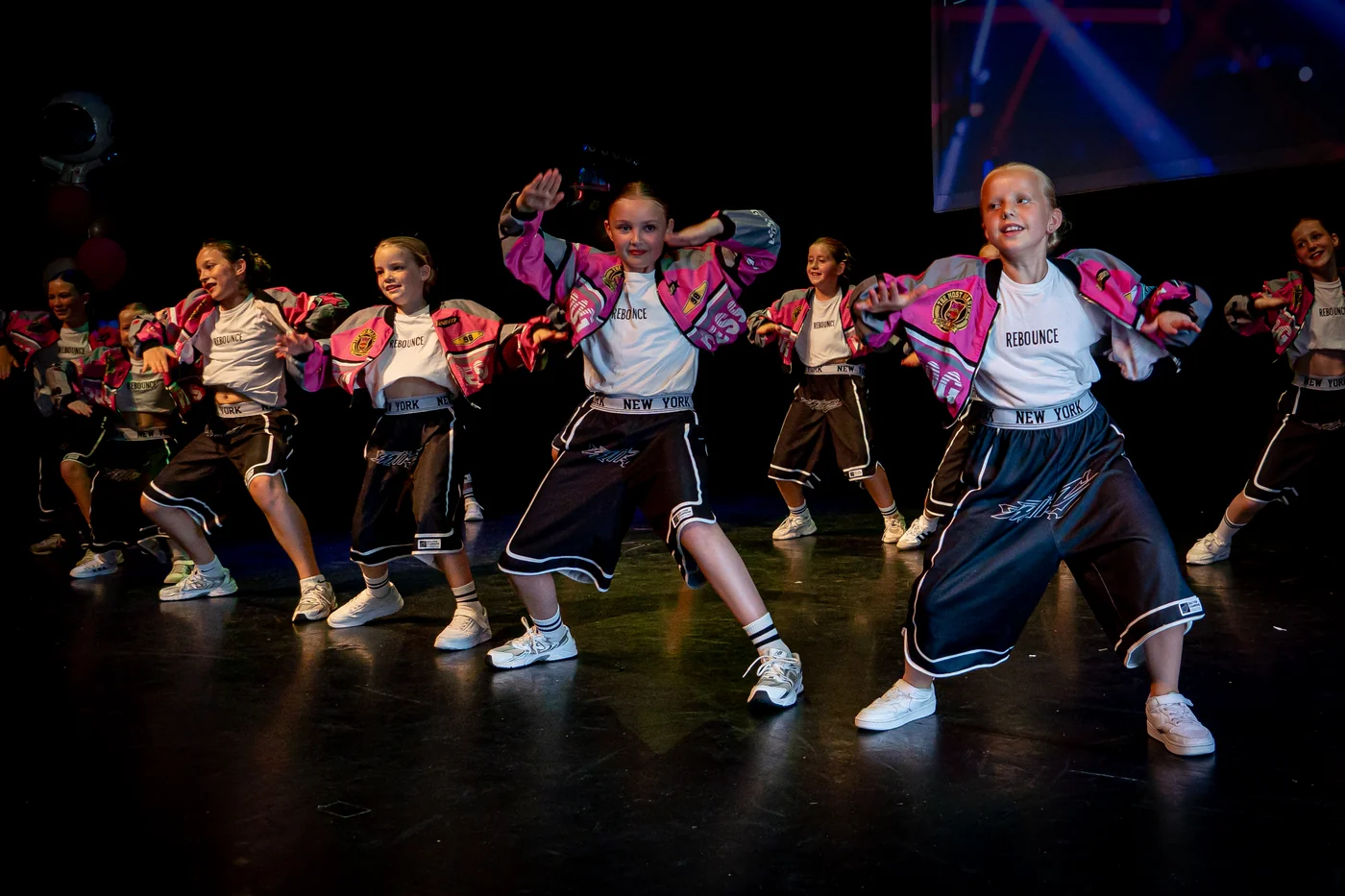 Een groep jonge Rebounce-dansers in roze jasjes tijdens de eindvoorstelling