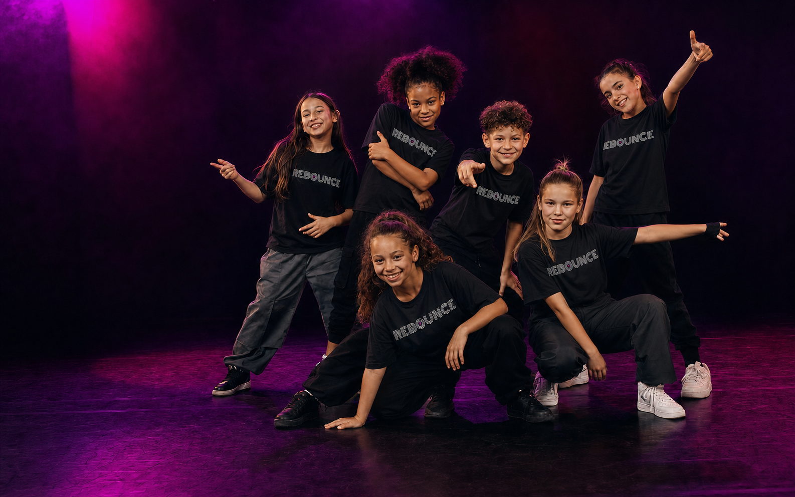 Een enthousiaste groep jonge dansers in zwarte Rebounce-shirts